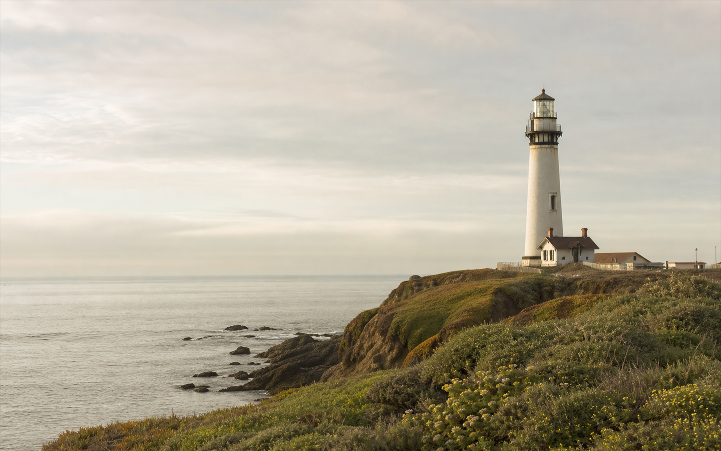 A guarded coastal lighthouse standing over steady water