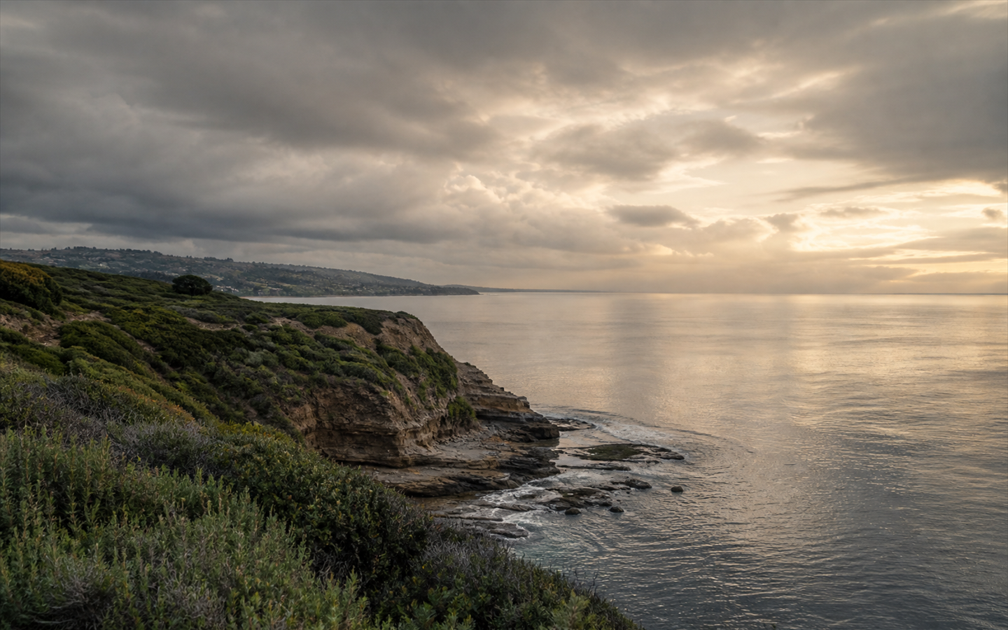 Storm clouds clearing over a calm stretch of Pacific coastline